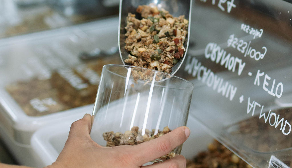 Pouring granola into glass jar | healthy breakfast mix, oats, seeds, and nuts | Sunshine Coast Wholefoods