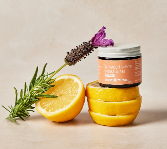 Jar of whipped tallow moisturizer with lemons and lavender on a beige background